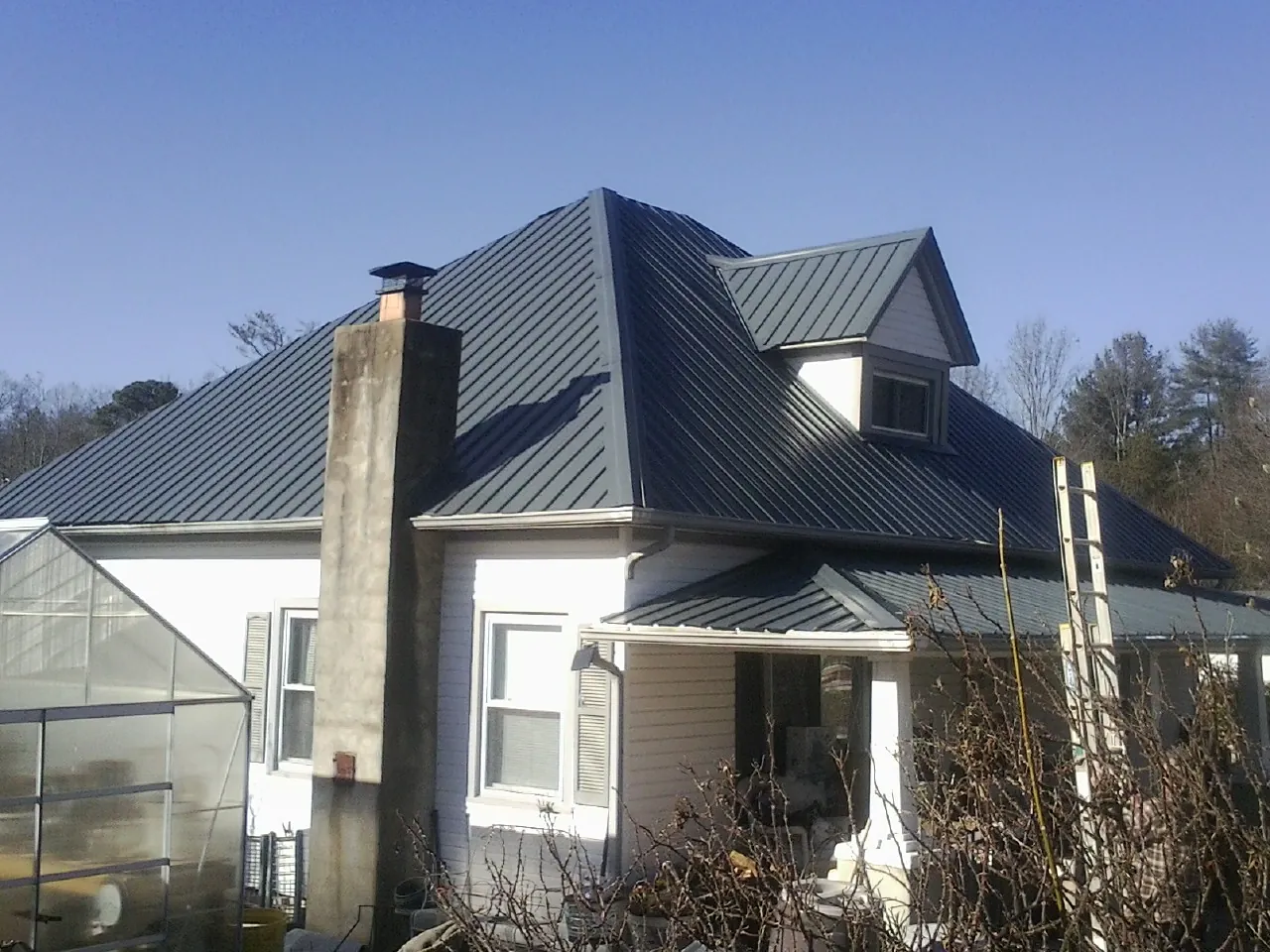 Dark blue standing seam metal roof on a white farmhouse with dormer — Slate & Tile Roof Repair by Roofing Brothers in Smiths Grove