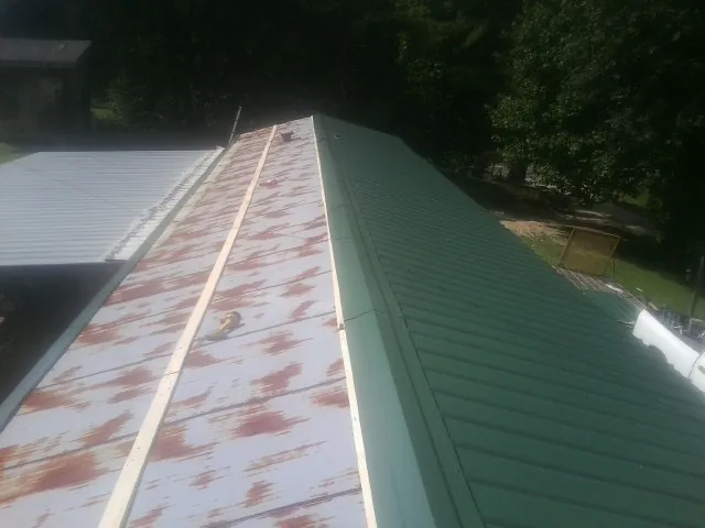 Old rusted panels beside newly installed green metal roofing — Wind Damage Roof Repair by Roofing Brothers in Smiths Grove