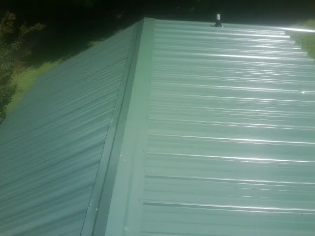 New green metal panels meeting at the ridge of a roof — Flat Roof Repair work by our crew in Smiths Grove