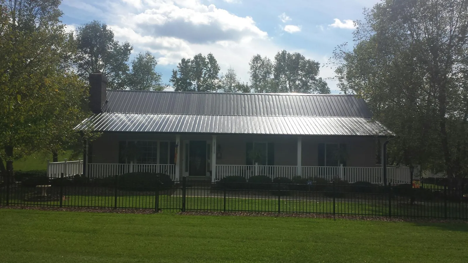 Gray metal roof on a brick ranch with a full width front porch — Gutter Guard Installation work by our crew in Smiths Grove