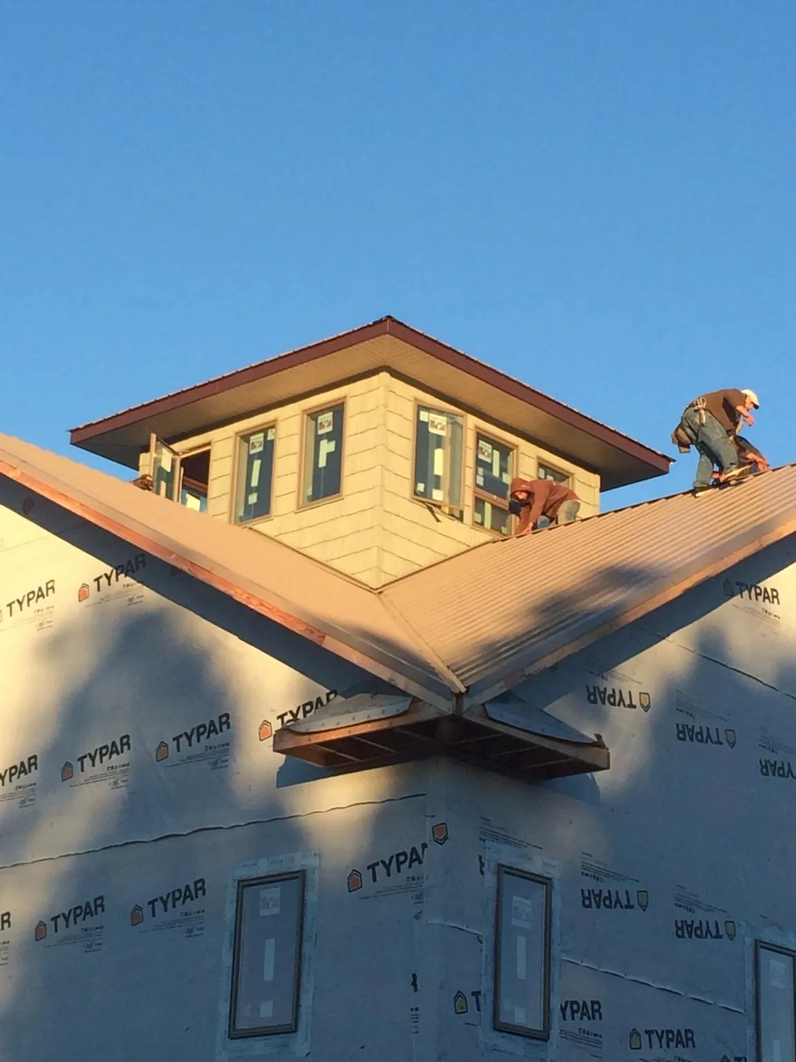 Roofers working around a rooftop cupola on a new metal roof at sunset — Roof Waterproofing in Smiths Grove by Roofing Brothers